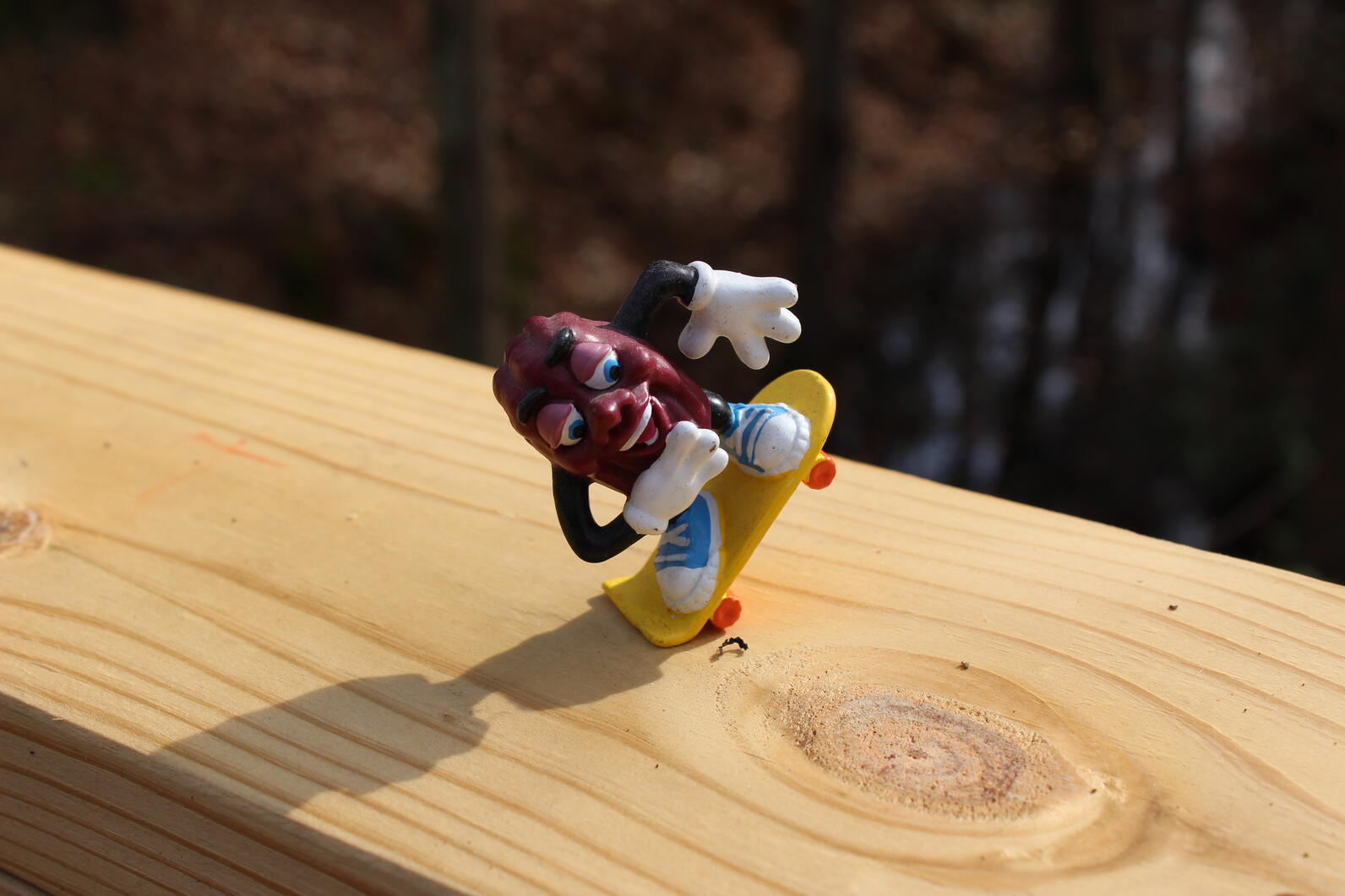 A toy of a California Raisin on a skateboard skates heedless of the sheer drop off on either side of the handrail, a clear sign of hubris disregarding risks in pursuit of adrenaline.