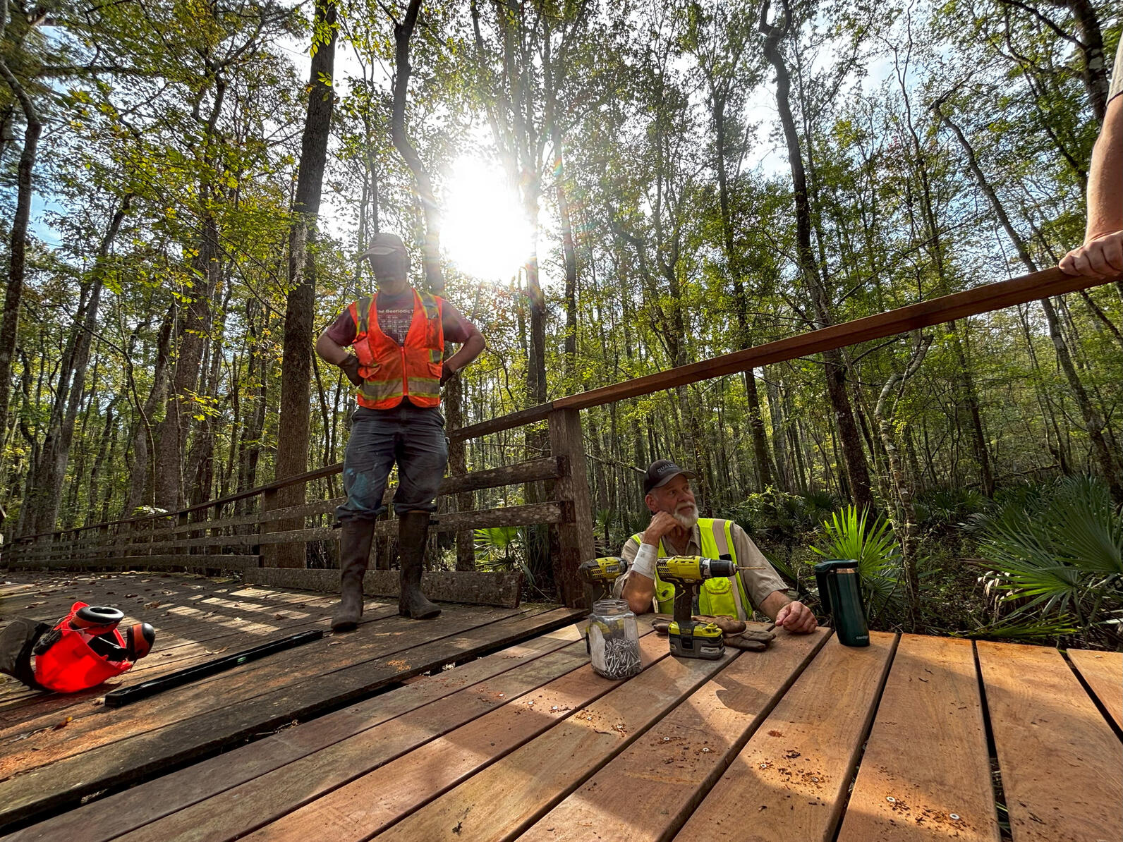 Mark stands on the boardwalk, surveying his work, while leaning on the side of the path is Rick, his head supported by his hand.