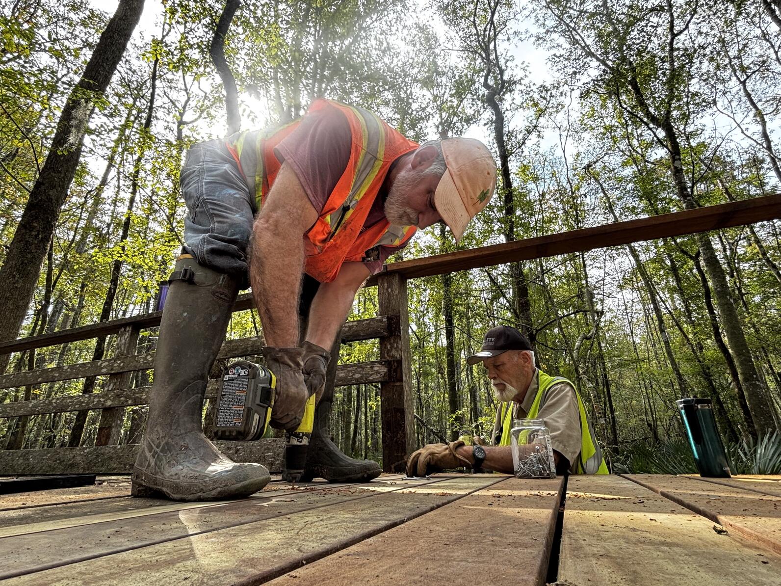 Mark Musselman and Rick Armstrong drive the final screws into the new pieces of wood to complete the boardwalk repair. 